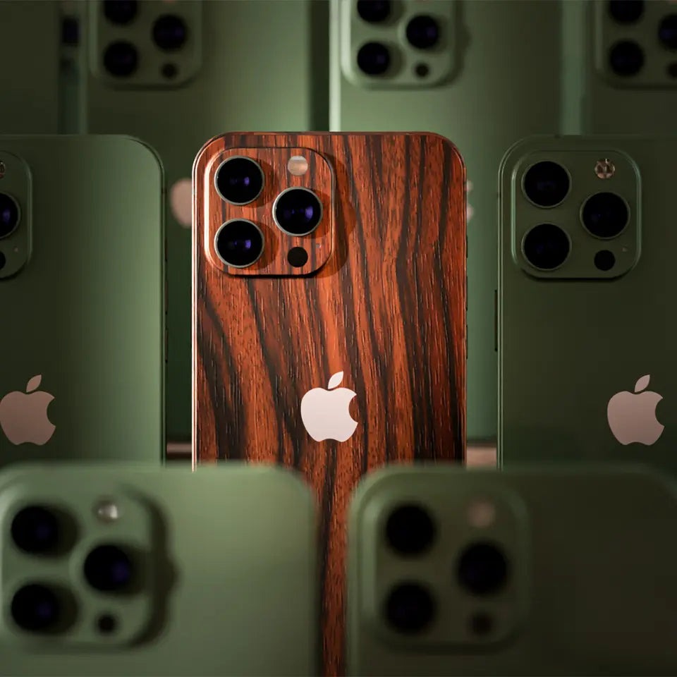 Close-up of a group of iPhones standing vertically next to each other. All the iPhones have a clear case except for one in the center. The center iPhone has a wooden skin applied to the back, making it stand out from the others